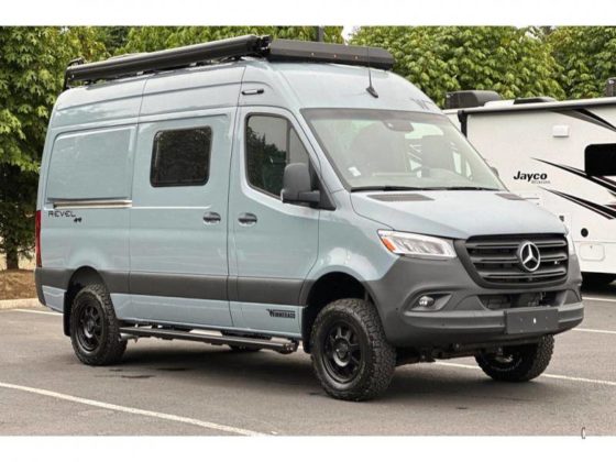 Photo of a gray Winnebago Revel 4x4 camper van in an RV Dealer parking lot