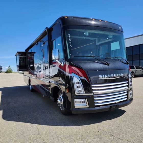 Image of a 2023 Winnebago Adventurer. Black with silver and burgundy accents.