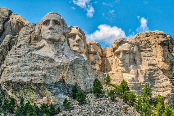Photo of Mount Rushmore featuring the images of George Washington, Thomas Jefferson, Teddy Roosevelt and Abraham Lincoln carved into the mountainside.