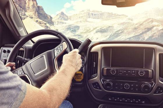 Man driving a car truck or motorhome on a rural road through the mountains with a view through the windshield